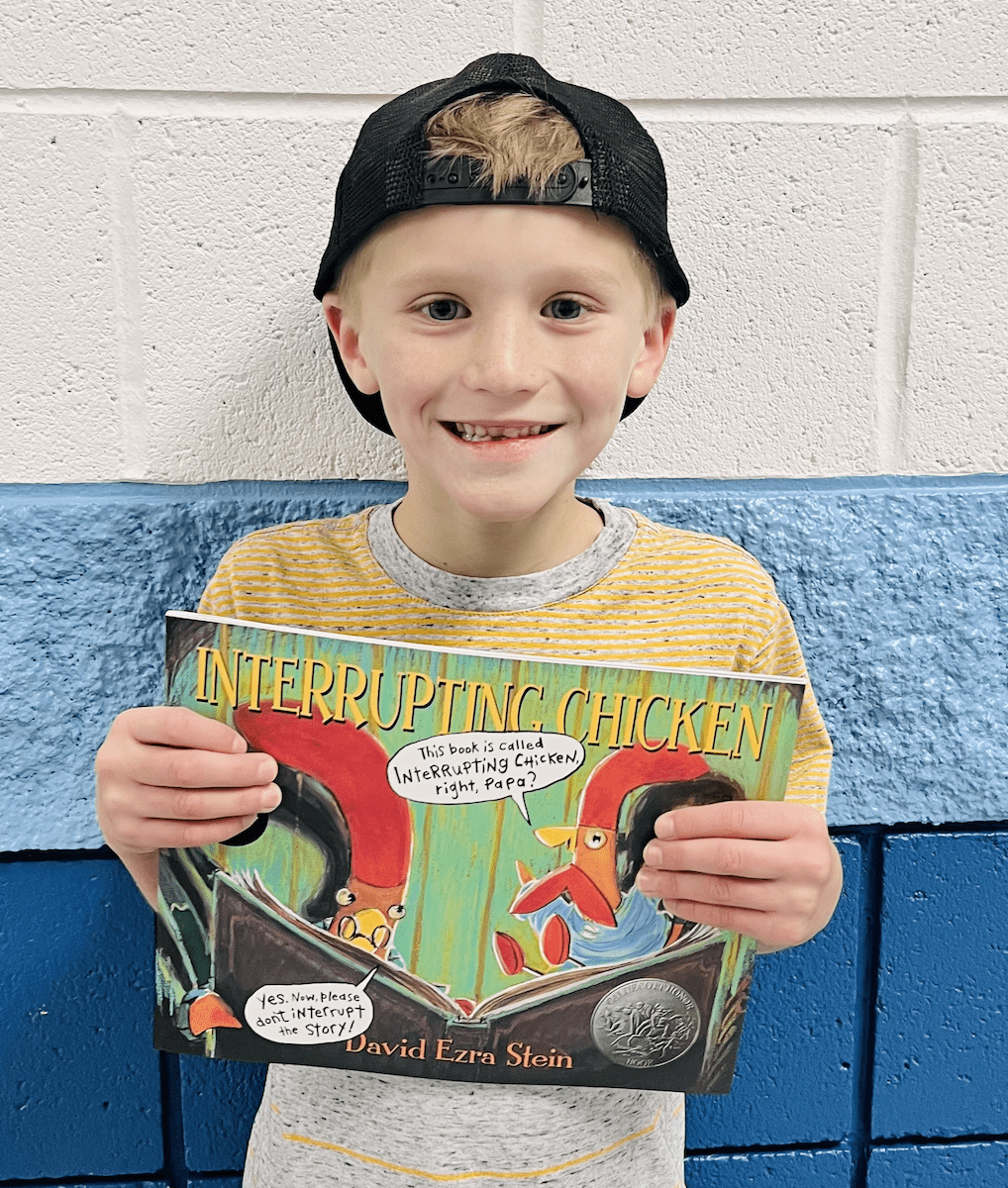 student holding a book received for earning a  praise award